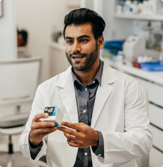 A pharmacist smiling while reviewing a medication box.