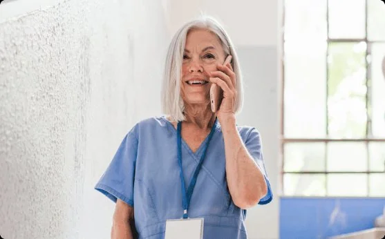 Healthcare professional in blue scrubs talking on a mobile phone